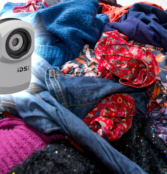 uEye XC camera in front of a mountain of old clothes