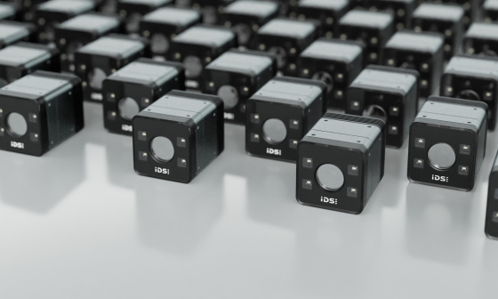 Industrial cameras in cube form lie in rows on a reflective surface.