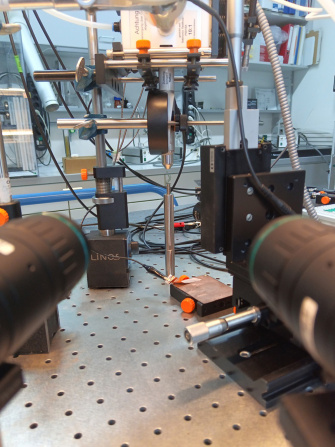 Experimental setup on an optical table with two side-mounted cameras and a plasma source