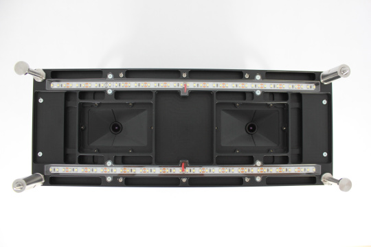 Underside of a black module with LED strips, lenses, and metal handles