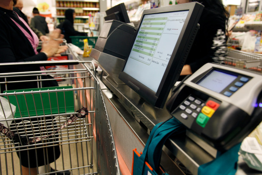 Woman with shopping trolley at a self-service checkout
