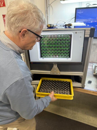 Test bench with screen and Eurobox containing metal parts for quality control.