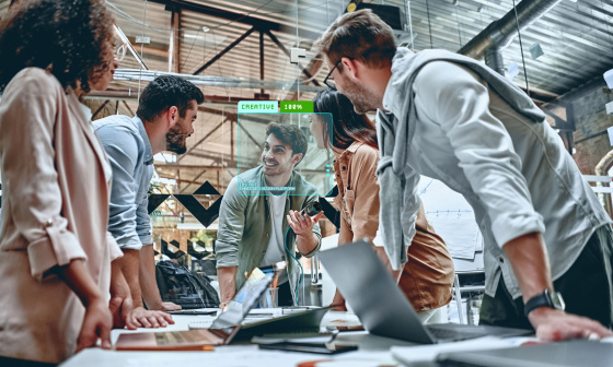 Collaboration: 5 people are standing together at a desk with laptops.