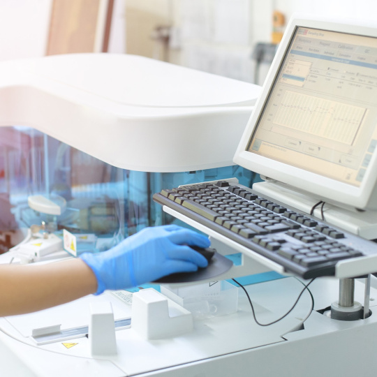 Computer in the laboratory, operated by a person wearing a blue glove.