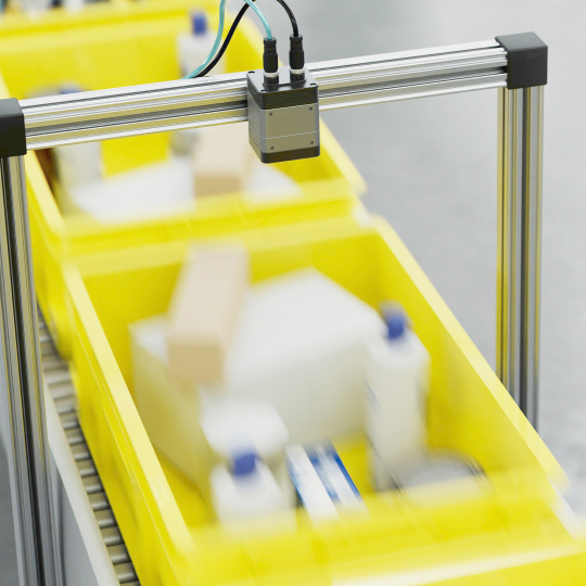 Industrial conveyor with camera over boxes, motion blur