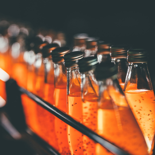 Glass bottles on a shelf containing orange liquid.