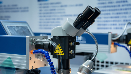 Binocular microscope with tubing and a lamp in a laboratory setup.