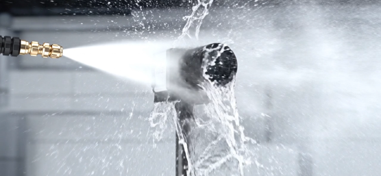 An industrial camera is sprayed with a powerful jet of water from close range.