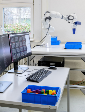 There are 2 screens in front of the robot sorting screws from blue containers.