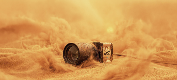 IDS industrial camera in sand amid dust clouds