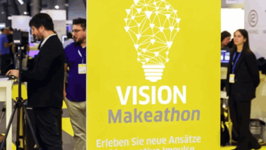Yellow banner “VISION Makeathon” with lightbulb graphic at expo