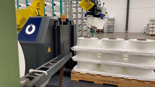 Robot arm sorts paper rolls on a pallet