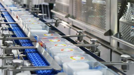 Packaged food containers moving along an automated conveyor line