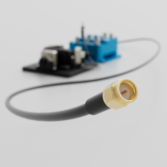 Gold-colored coaxial plug and cable in front of a blurred circuit board