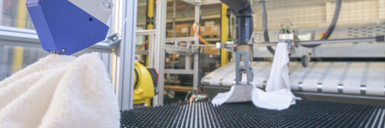 Yellow robotic arms with towels in laundry using IDS industrial cameras.