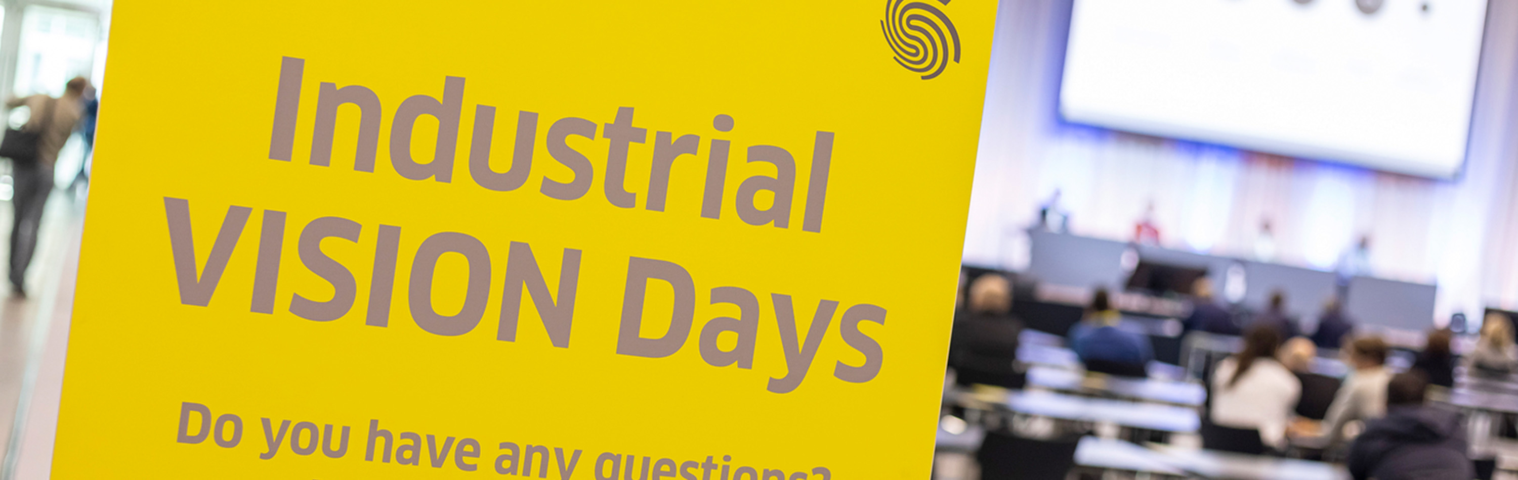 Schrift Industrial Vision Days mit Vortragsraum verschwommen im Hintergrund.